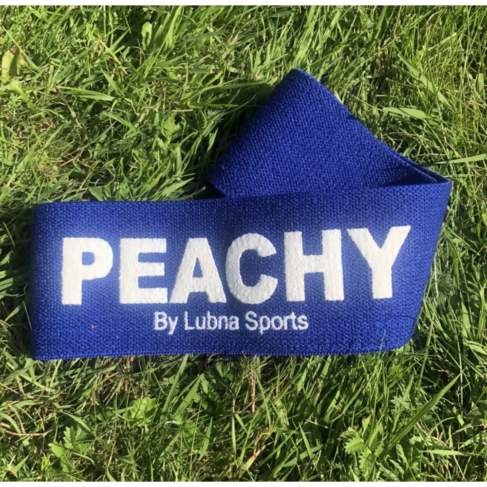 Blauwe stoffen band met ’PEACHY By Lubna Sports’ gedrukt in witte tekst.